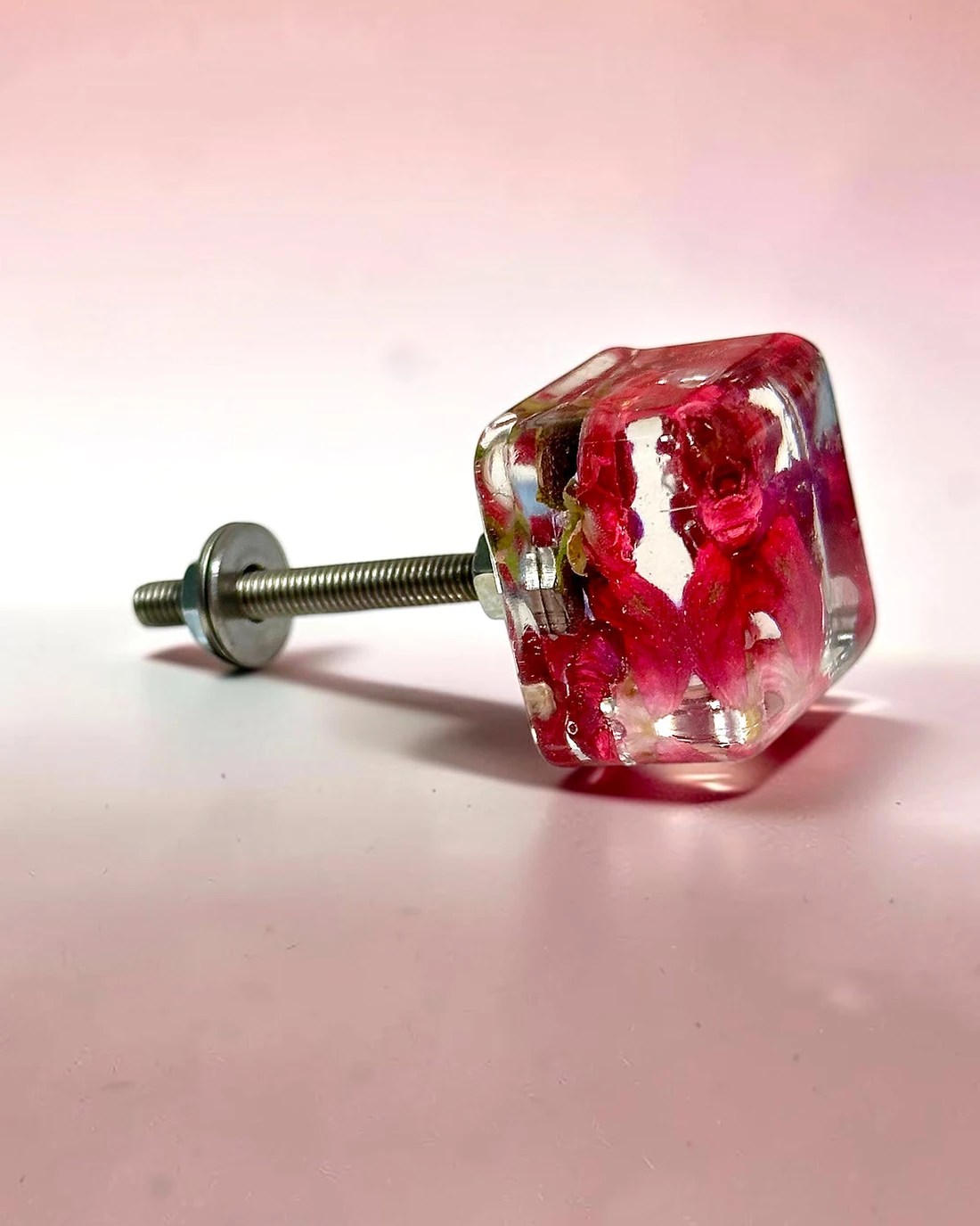 Gałka meblowa Róża (Rosa) · gałka ze śrubą, z boku, na jasnoróżowym tle